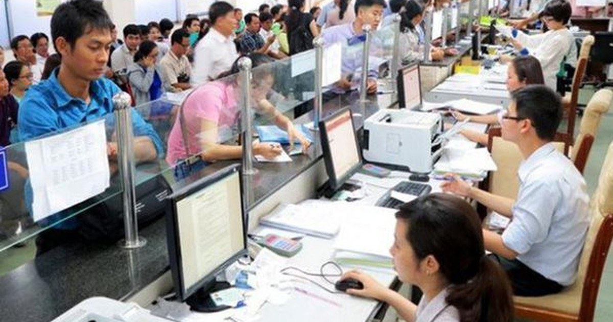 Người dân và cán bộ làm việc tại quầy tiếp nhận hồ sơ với máy tính